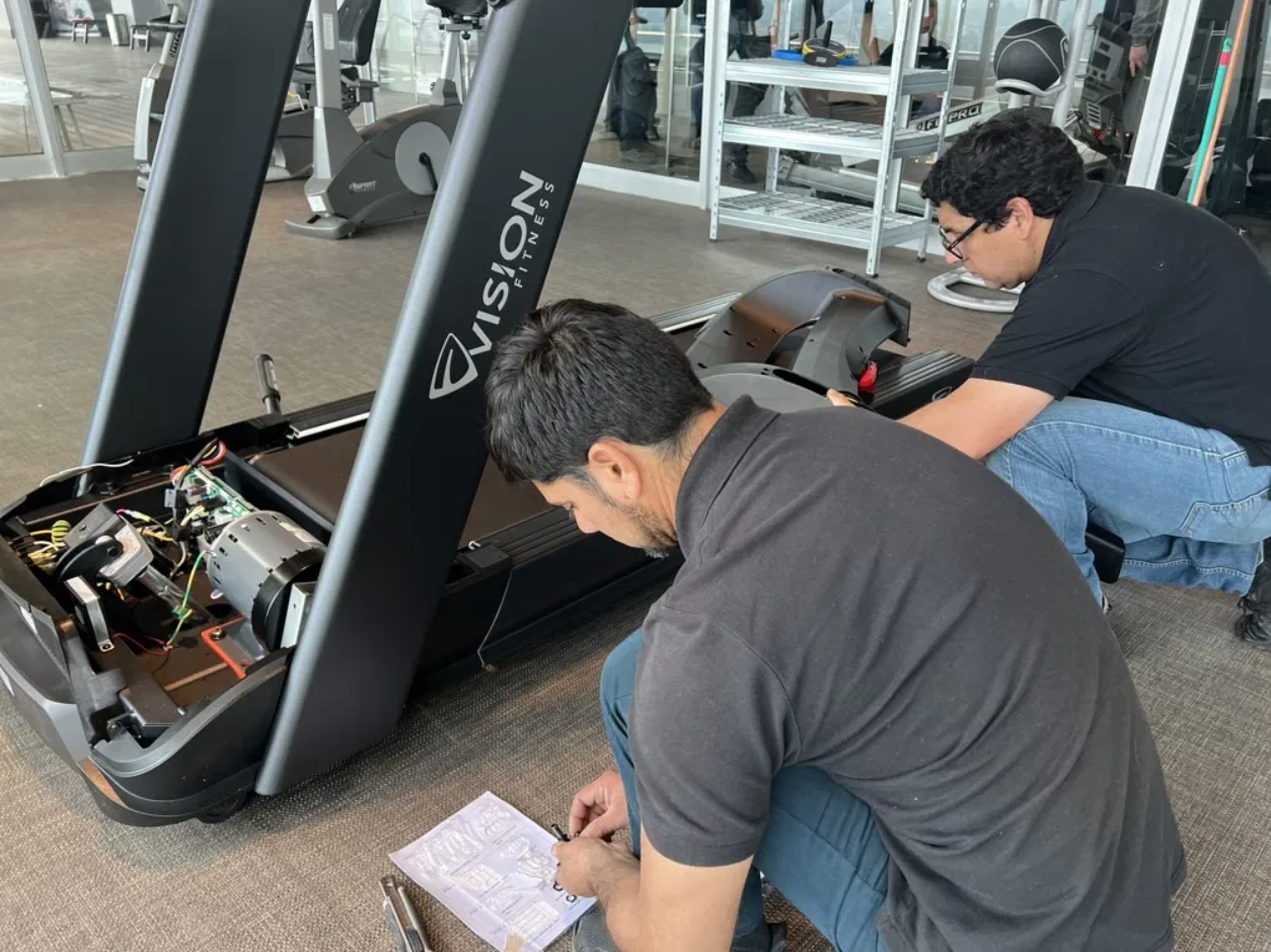 Técnico de M4 Fitness revisando componentes de un equipo